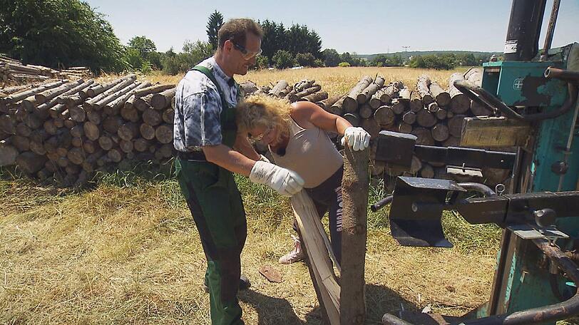 Monika hilft dem sanften Ackerbauer Markus 'Muck' (40) beim Holzspalten.