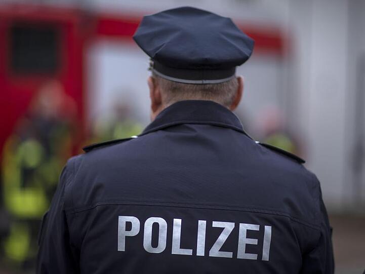 Polizisten stehen vor einem Polizeifahrzeug. Foto: Jens Büttner/zb/dpa