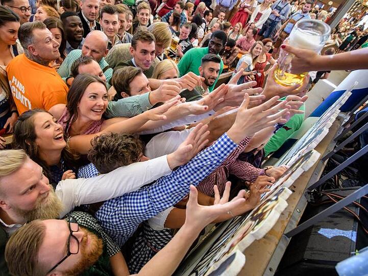 Besucher freuen sich im Paulaner-Festzelt auf ihr erstes Bier.