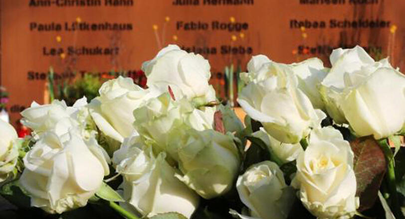 Weiße Rosen vor einer Gedenktafel mit den Namen der Opfer des Germanwings-Absturzes in Haltern am See.
