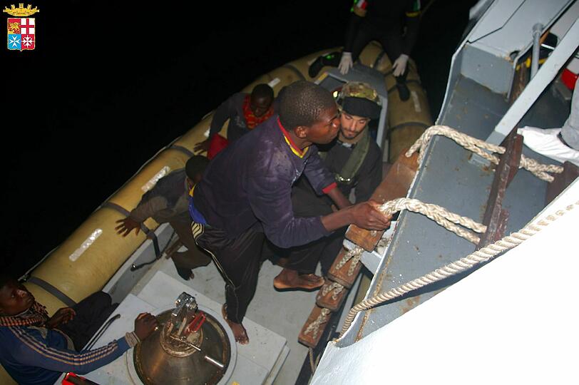 Ein Mann steigt aus einem Flüchtlingsboot - er ist einer von Tausenden Flüchtlingen, die seit Anfang der Woche von der italienischen Marine an Bord genommen wurden.