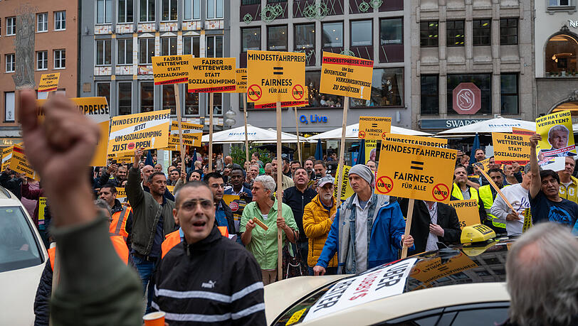 Sollen Mindestentgelte für Fahrdienst-Vermittler wie Uber und Bolt eingeführt werden? Münchner Taxifahrer demonstrieren auf dem Marienplatz.