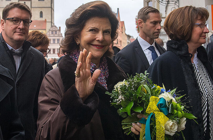 Königin Silvia von Schweden winkt auf dem Marktplatz in Wittenberg (Sachsen-Anhalt) vor den Türmen der Stadtkirche. In Wittenberg besichtigt das schwedische Königspaar die Schloss- und Stadtkirche. Beide Kirchen sind mit dem Wirken des Reformators Martin Luther verbunden.