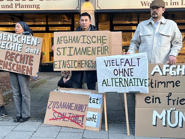 Afghanen am Rand des Verdi-Gedenkens mit Schildern.