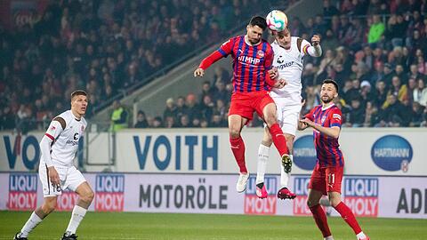 Heidenheims Tim Kleindienst (3.v.r) steigt gegen St. Paulis Jackson Irvine (2.v.r) zum Kopfball hoch.