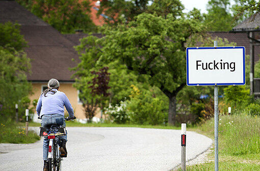 Ein Radfahrer fährt am Ortsschild von Fucking in Oberösterreich vorbei.