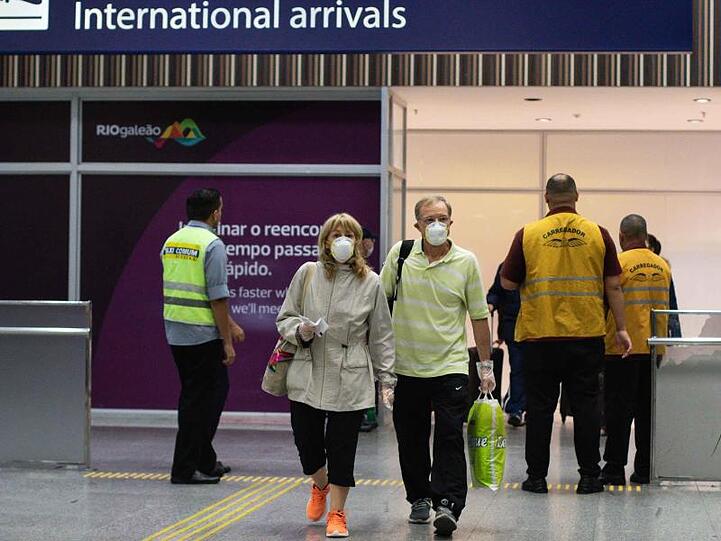 Passagiere mit Mundschutz bei ihrer Ankunft am Flughafen von Rio de Janeiro.