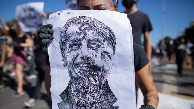 Einige Demonstranten werfen dem brasilianischen Präsidenten wegen seiner Tatenlosigkeit Genozid vor. Auf diesem Protestplakat verschwimmt Bolsonaros Gesicht mit dem Hitlers. Einige Demonstranten werfen dem brasilianischen Präsidenten wegen seiner Tatenlosigkeit Genozid vor. Auf diesem Protestplakat verschwimmt Bolsonaros Gesicht mit dem Hitlers.