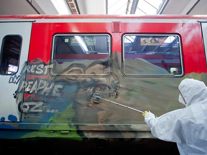 Ein Mitarbeiter reinigt einen mit Graffiti bemalten Waggon. Foto: Daniel Bockwoldt/Archiv