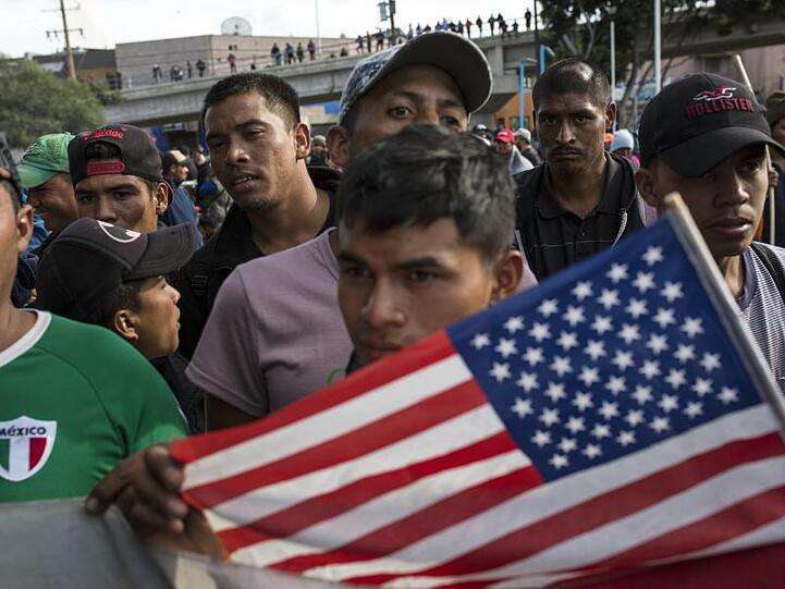 Ein Migrant mit der US-Flagge am Grenzübergang Mexiko-USA im mexikanischen Tijuana.