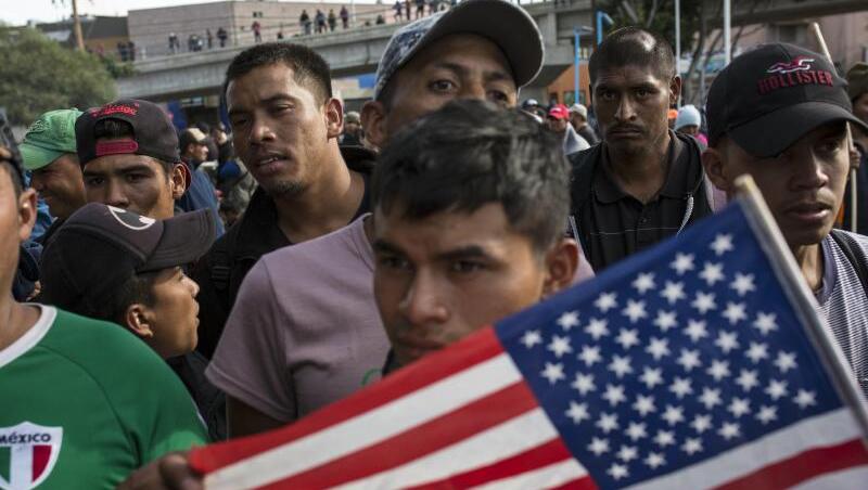 Ein Migrant mit der US-Flagge am Grenzübergang Mexiko-USA im mexikanischen Tijuana.