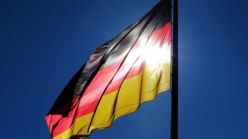 Bei strahlendem Sonnenschein weht am unter einem tiefblauen Himmel vor dem Reichstagsgebäude in Berlin die Deutschlandfahne.