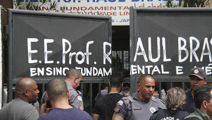 Polizisten bewachen den Eingang der Raul Brasil State School. Zwei vermummte Jugendliche hatten die Schule gestürmt und das Feuer eröffnet. Polizisten bewachen den Eingang der Raul Brasil State School. Zwei vermummte Jugendliche hatten die Schule gestürmt und das Feuer eröffnet.