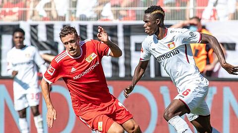 Unions Max Kruse (l) kämpft mit dem Leverkusener Neuzugang Odilon Kossounou um den Ball.