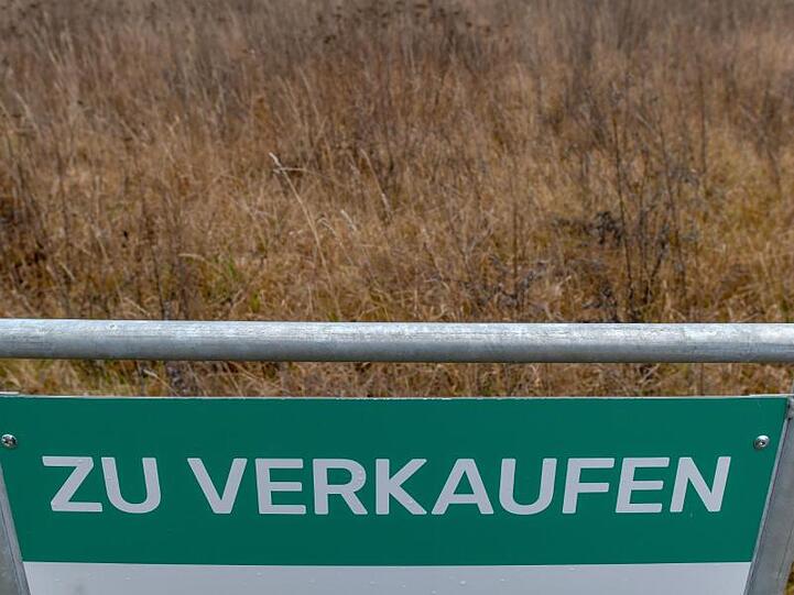Ein Schild mit der Aufschrift "Zu verkaufen" steht an einem leeren Grundstück. Foto: Patrick Pleul/Archivbild