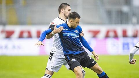 Paderborns Julian Justvan (r) schirmt den Ball vor Sandhausens Pascal Testroet ab.