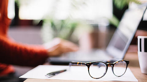 Eine Brille liegt an einem Homeoffice-Arbeitsplatz.
