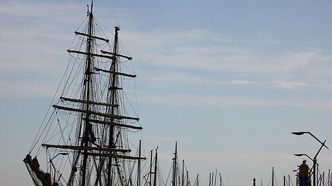 Menschen gehen bei sonnigem Wetter am Hafen von Eckernförde spazieren.