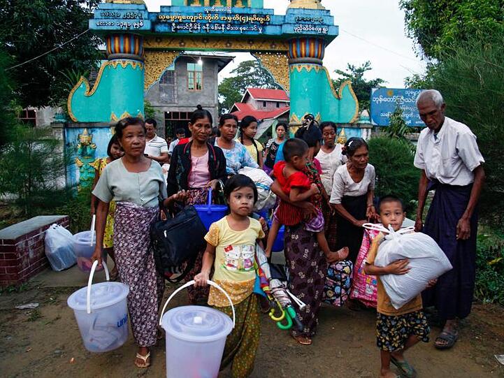 Rohingya, die aus dem Kampfgebiet geflohen sind, tragen ihr Hab und Gut bei der Ankunft in einem Kloster.