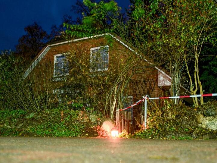 Eine Grableuchte steht neben einer Polizeiabsperrung am Eingang zu einem Haus in Wittenburg. Hier ist ein 85 Jahre alter Mann mit einem Messer getötet worden.