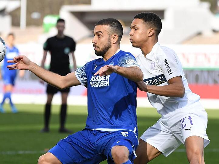 Der Karlsruher Burak Camoglu (l) versucht den Ball vor dem Osnabrücker Felix Agu abzuschirmen.
