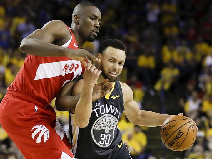 Stephen Curry (r) von den Golden State Warriors behauptet sich gegen Serge Ibaka von den Toronto Raptors.