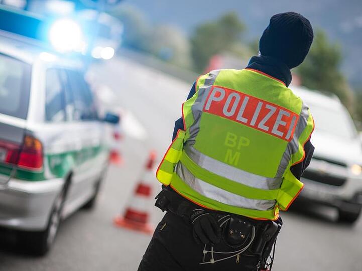 Ein Polizeibeamter beobachtet an einer Grenzkontrolle Fahrzeuge, die von Österreich nach Deutschland kommen. Foto: Matthias Balk/Archivbild