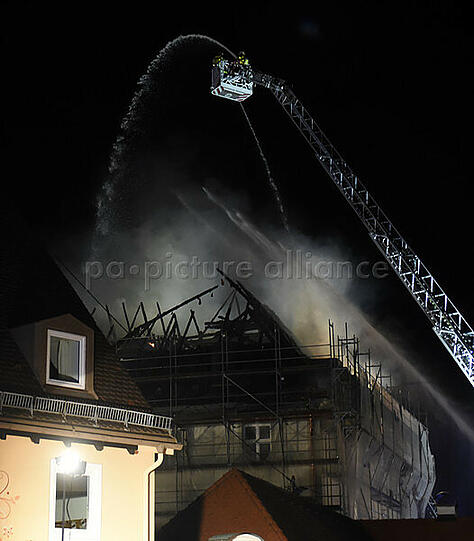 Feuerwehrleute löschen im Bereich des Klosters Rottenbuch den Dachstuhl eines Gebäudes, der in voller Ausdehnung brennt.