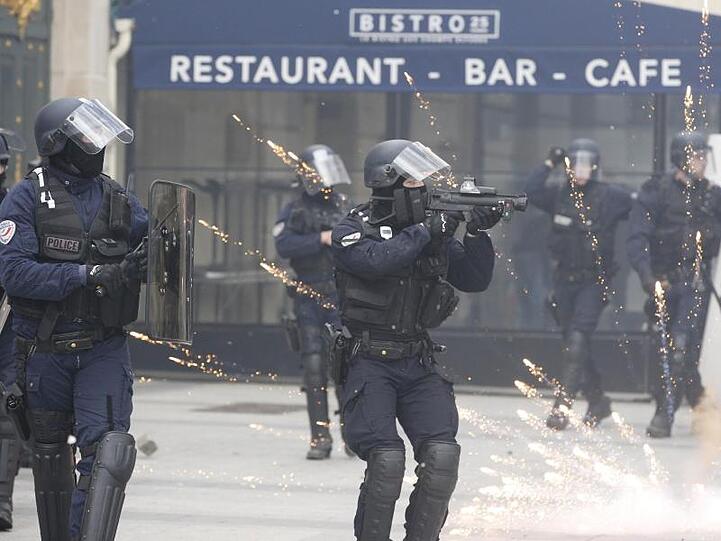 Ein Polizist zielt bei den "Gelbwesten"-Protesten auf den Champs-Elysees auf Demonstranten.