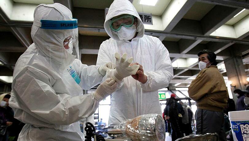 Auch die Bewohner aus der Umgebung des Reaktors werden von Männern in Strahlenschutzkleidung auf Radioaktivität untersucht. Auch die Bewohner aus der Umgebung des Reaktors werden von Männern in Strahlenschutzkleidung auf Radioaktivität untersucht.