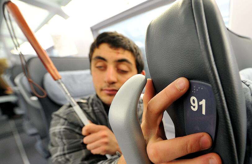 Der blinde Muhamed (16) tastet die Nummer eines Sitzes, die in erhöhter Schrift und Blindenschrift angebracht ist.