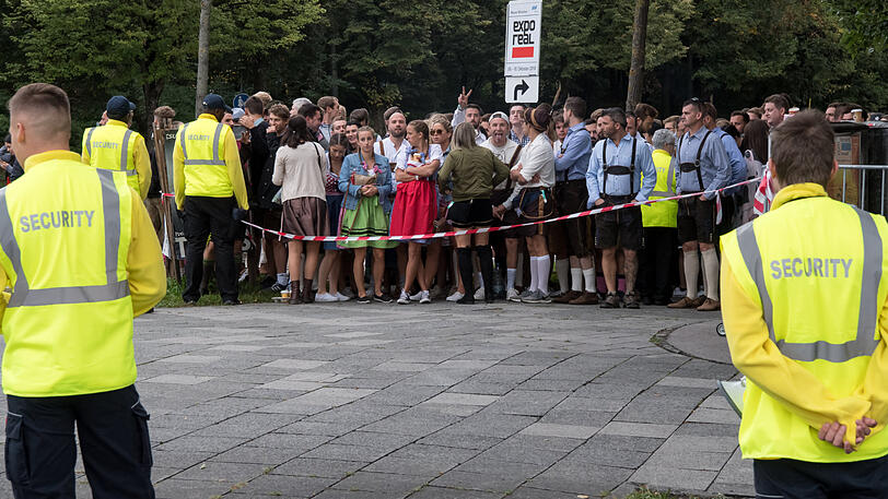 Wiesn-Besucher warten in den frühen Morgenstunden vor dem Oktoberfestgelände auf den Einlass.