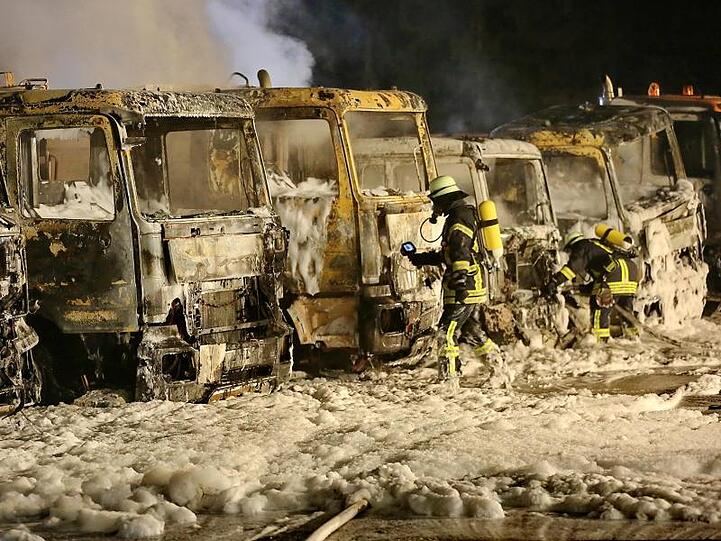 Feuerwehrleute sind vor sieben ausgebrannten Lastwagen im Einsatz. Foto: Ralf Zwiebler