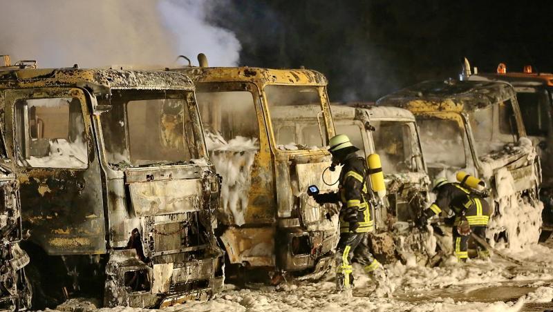 Feuerwehrleute sind vor sieben ausgebrannten Lastwagen im Einsatz. Foto: Ralf Zwiebler Feuerwehrleute sind vor sieben ausgebrannten Lastwagen im Einsatz. Foto: Ralf Zwiebler