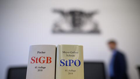 Eine Ausgabe des Strafgesetzbuchs und der Strafprozessordnung stehen in einem Gerichtssaal.