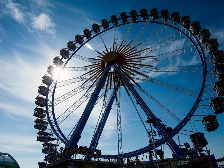 Die Sonne scheint auf dem Oktoberfestgelände, hinter einem Riesenrad. Foto: Peter Kneffel/Archivbild