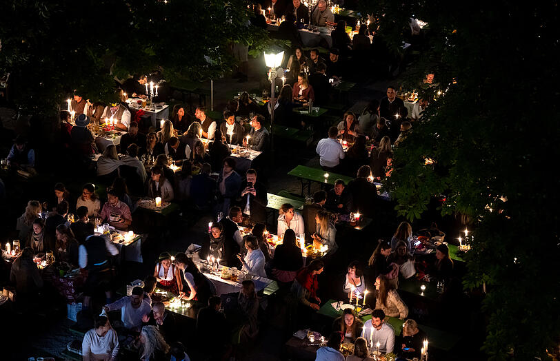 Zahlreiche Besucher des traditionellen Kocherlball sitzen am Chinesischen Turm im Englischen Garten an Biertischen.