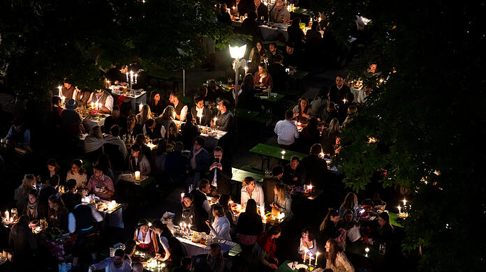Zahlreiche Besucher des traditionellen Kocherlball sitzen am Chinesischen Turm im Englischen Garten an Biertischen.