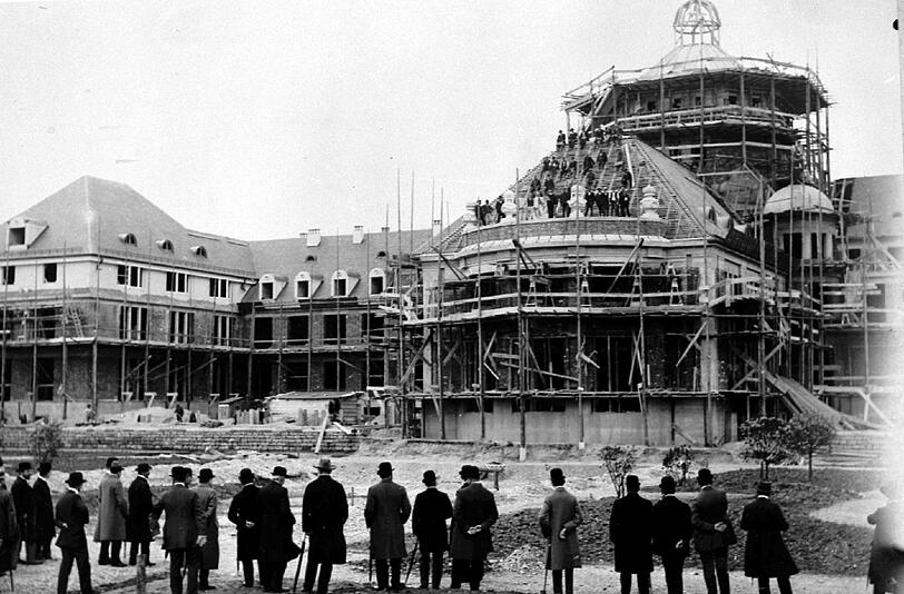 1912: Richtfest des Institutsgebäudes der Botanischen Staatsanstalten, Ansicht von der Sudseite (Gartenseite). An der Nordseite des Gartens gelegen ragt dieses monumentale,
im Munchner Jugendstil erstellte Bauwerk der Botanischen Forschungsanstalten mit seinem zentralen Teil in den Schmuckhof. Im Jahr 1912 wurde das Richtfest fur Kuppel und Horsaalbau gefeiert. Auf dessen Balustrade befanden sich Figuren, die heute fehlen.
Das Gebaude wurde 1913 fertiggestellt. Vom alten Botanischen Garten zogen um: das Botanische Laboratorium, das Pflanzenphysiologische Institut, das Herbarium und die Botanische Staatssammlung, die damals als &bdquo;Botanisches Museum&ldquo; dem Publikum zuganglich war.