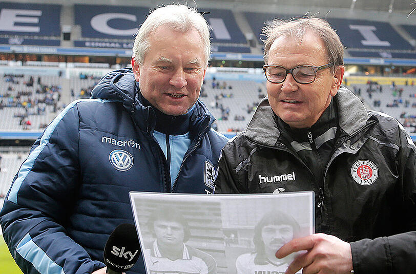Betrachteten ein Foto von sich als Spieler: St.-Pauli-Trainer Ewald Lienen (r.) und der ehemalige Löwen-Coach Benno Möhlmann in der vergangenen Saison - Lienen war einst ebenfalls bei den Giesingern aktiv.
