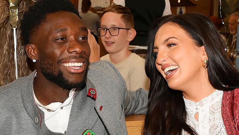 Alphonso Davies trägt einen herzigen Chef-Anstecker. Freundin Sheyenne amüsiert's. Alphonso Davies trägt einen herzigen Chef-Anstecker. Freundin Sheyenne amüsiert's.