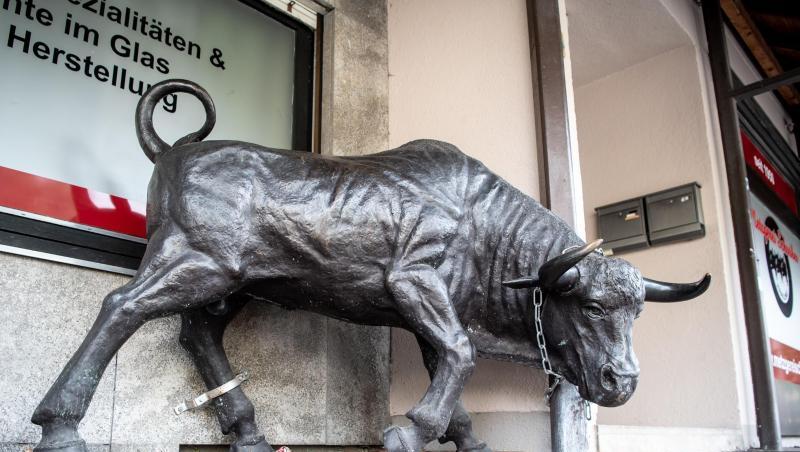 Eine Stier-Skulptur aus Bronze steht vor einer Metzgerei.