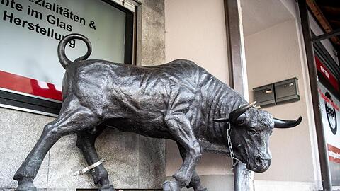 Eine Stier-Skulptur aus Bronze steht vor einer Metzgerei.