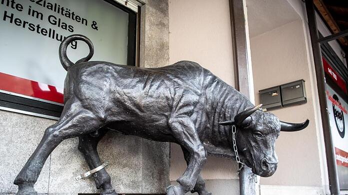 Eine Stier-Skulptur aus Bronze steht vor einer Metzgerei.