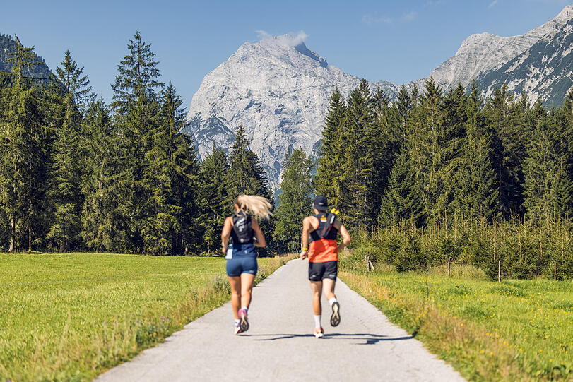 Zwei Läufer nutzen das schöne Wetter, um im Naturpark Karwendel mit Blick auf das Sonnjoch zu laufen.
