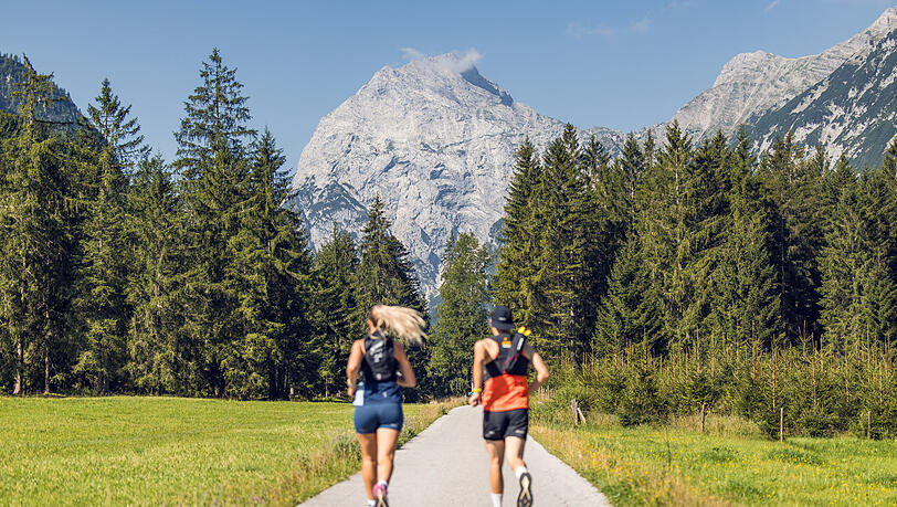 Zwei Läufer nutzen das schöne Wetter, um im Naturpark Karwendel mit Blick auf das Sonnjoch zu laufen. Zwei Läufer nutzen das schöne Wetter, um im Naturpark Karwendel mit Blick auf das Sonnjoch zu laufen.