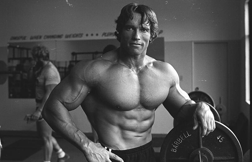 1976: Arnold Schwarzenegger zeigt seine Muskeln bei den Dreharbeiten zur berühmten Bodybuilder-Dokumentation &bdquo;Pumping Iron&ldquo;.