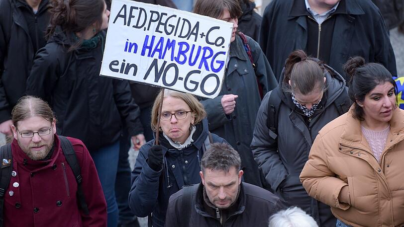 Teilnehmer einer Gegendemonstration zu einer "Merkel muss weg!" - Kundgebung halten ein Schild mit der Aufschrift "AFD.Pegida und Co In Hamburg ein No-Go" in die Höhe.