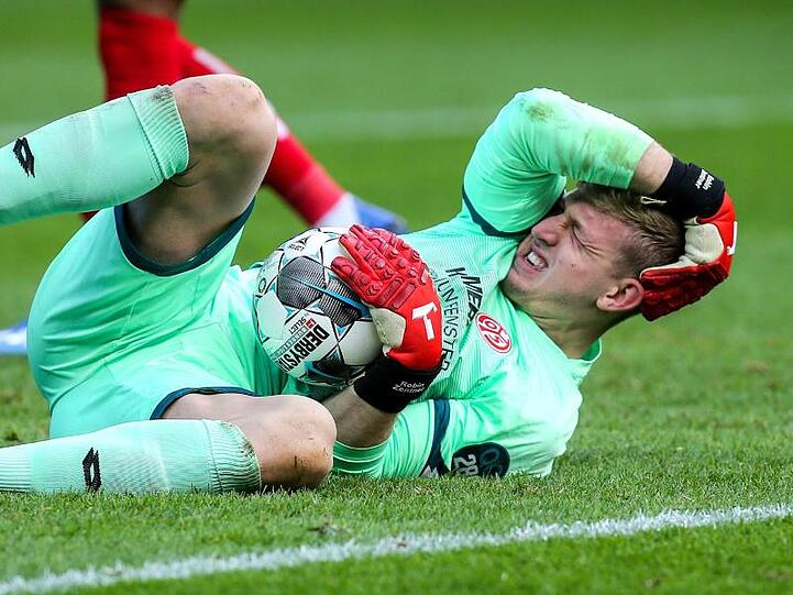 Torwart Robin Zentner von Mainz 05 hält sich nach einem Zusammenstoß den Kopf.
