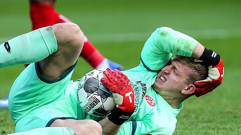 Torwart Robin Zentner von Mainz 05 hält sich nach einem Zusammenstoß den Kopf.